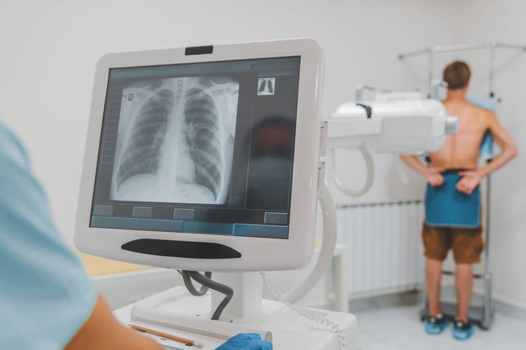 X-Ray Technologist Performing Back X-Ray On Male Patient
